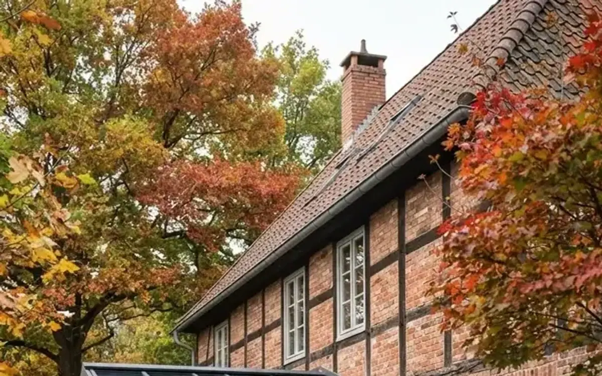 Glasanbau mit Glasdach an einem Backstein-Altbau im Herbst
