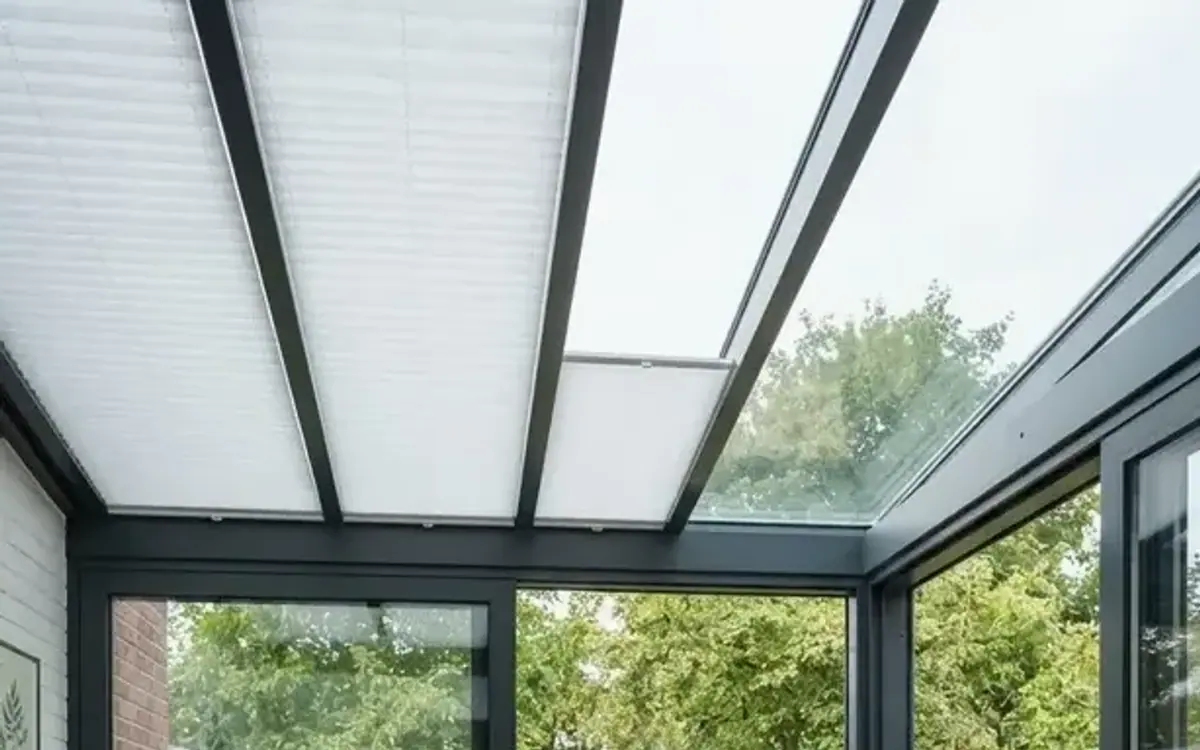 Wintergarten mit hellem Plissee unter dem Glasdach