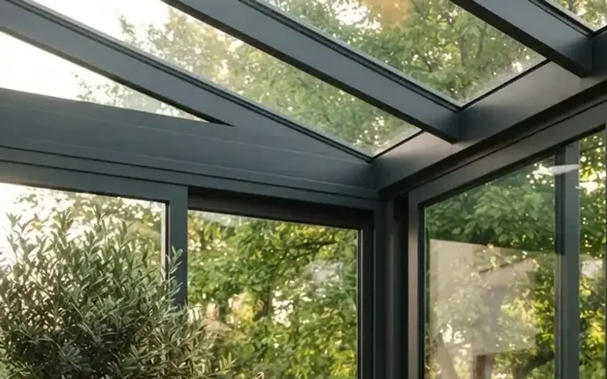 Wintergarten mit Glasdach und Blick auf Bäume im Garten