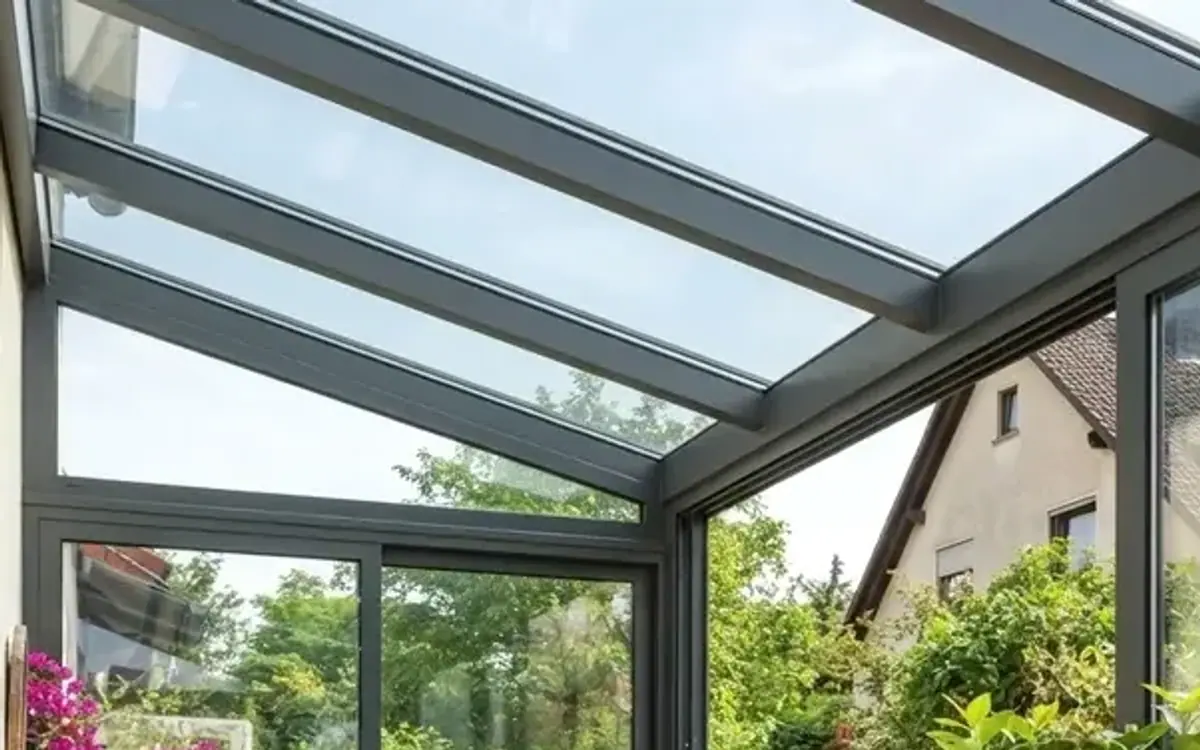 Wintergarten mit Glasdach und blühenden Pflanzen im Garten